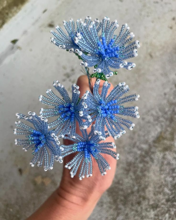 This may contain: three blue flowers are being held in someone's hand