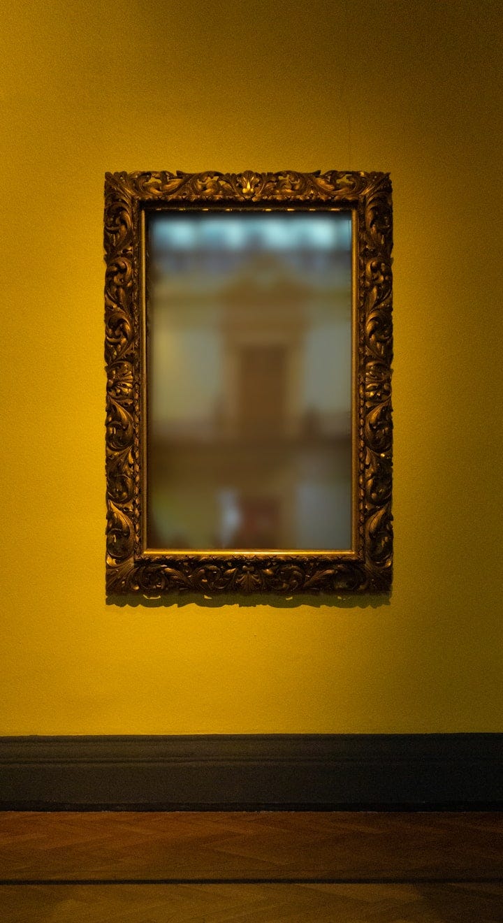 Framed mirror against yellow wall Framed mirror against yellow wall