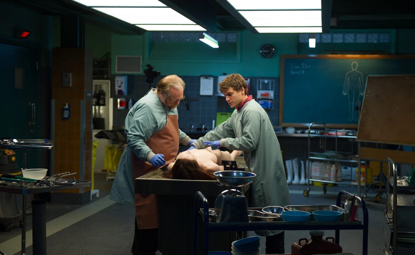 two men standing in a morgue over a dead woman