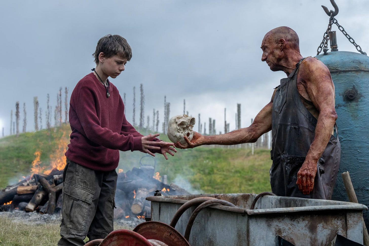 A man hands a young boy a skull.