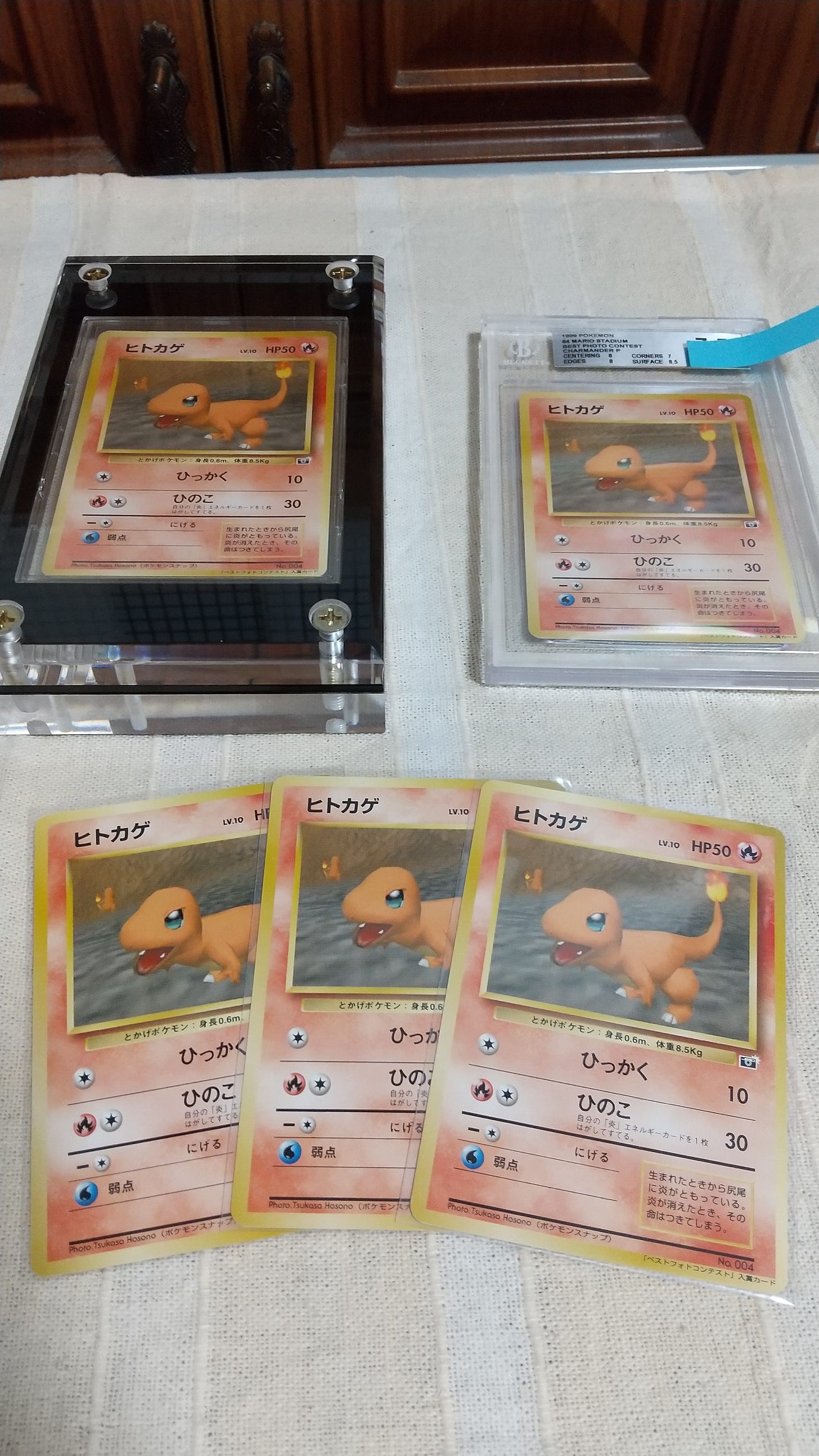 Five copies of Tsukasa's Charmander card. One copy inside of an acrylic frame, one graded copy, and three sleeved cards Five copies of Tsukasa's Charmander card. One copy inside of an acrylic frame, one graded copy, and three sleeved cards