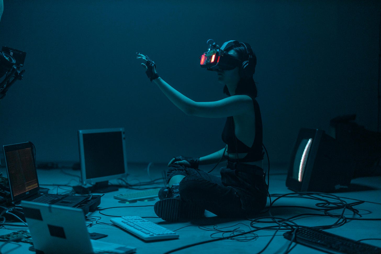Free Woman immersed in virtual reality, surrounded by tech, in a dimly lit room. Stock Photo