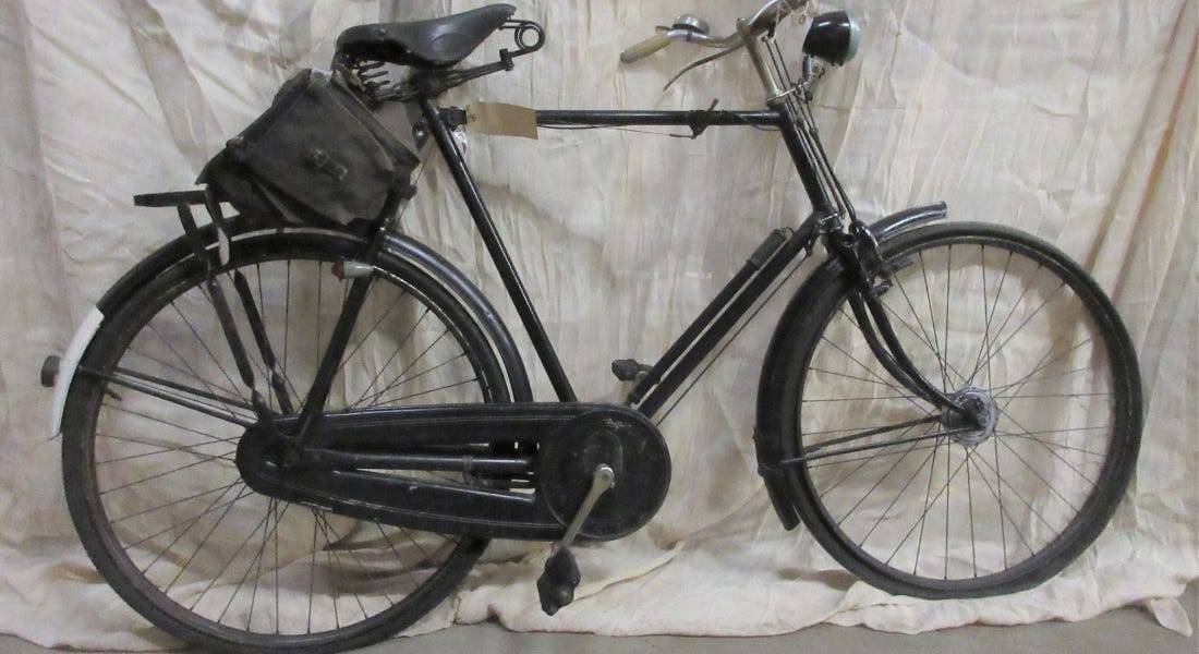 A black bike next to a white cloth A black bike next to a white cloth