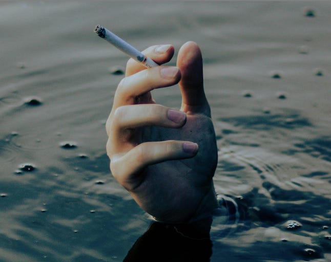Photo by Valeria November from https://www.pexels.com/photo/hand-with-cigarette-sticking-out-of-water-16265518/