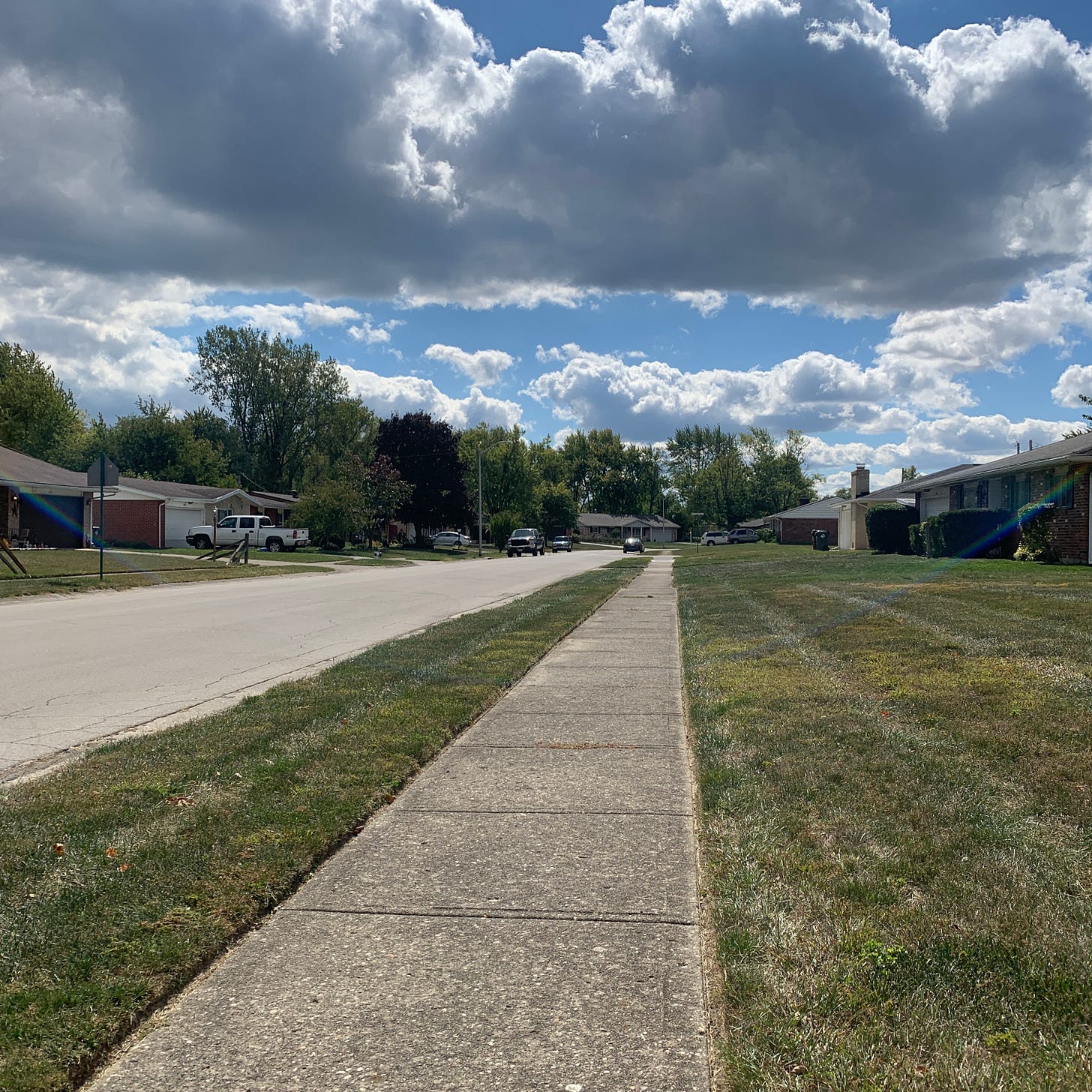 A sidewalk meeting the horizon with a blue sky filled with pillowy clouds. A sidewalk meeting the horizon with a blue sky filled with pillowy clouds.