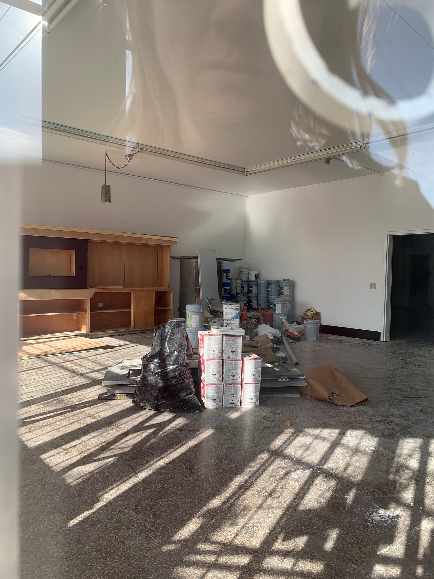 reflection of someone peering in a window to a vacant storefront