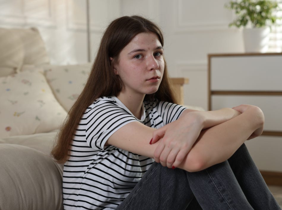 Girl with long brown hair in striped shirt, looking pensive