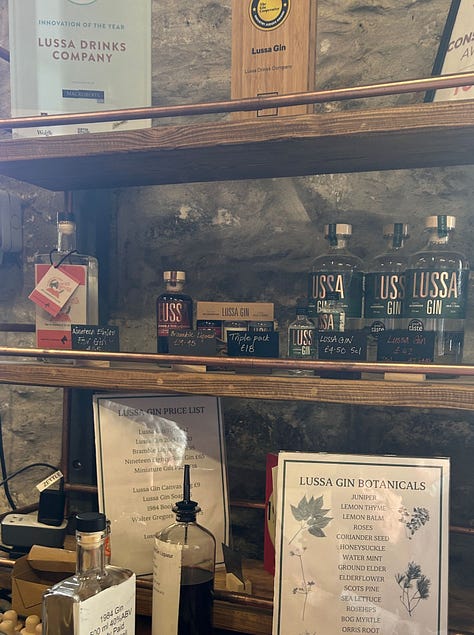 A box of flowers and leaves, a large copper still, shelves of bottles for sale