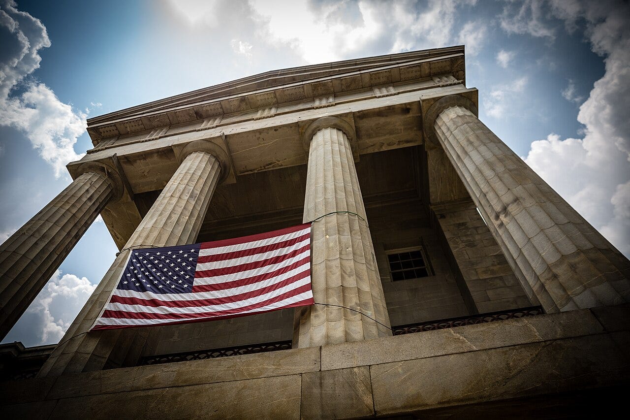 Looking up at the North Carolina State Capitol in Raleigh, with an American flag hung between its stone columns Looking up at the North Carolina State Capitol in Raleigh, with an American flag hung between its stone columns