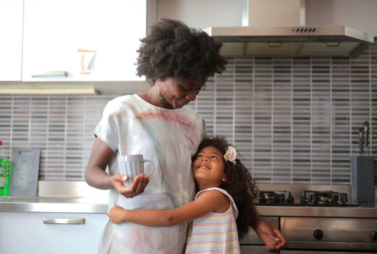 A joyful moment between mother and daughter in a modern kitchen setting.