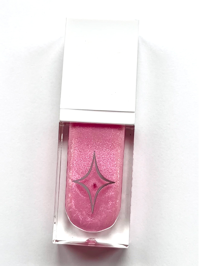 Product shot of Half Magic Magic Drip Glitter Lip Gloss in a shimmering pink shade with the signature star logo. Product shot of Half Magic Magic Drip Glitter Lip Gloss in a shimmering pink shade with the signature star logo.