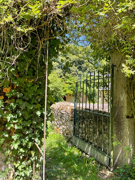 A collage of the grounds around the rented farmhouse, including an iron gate set into an ivy-covered stone wall, a garden path, a courtyard strung with bunting at dusk, two small children watching a rainbow from a doorway, pink cyclamen carpeting the ground beneath a large tree, and children walking down tree-lined country paths.