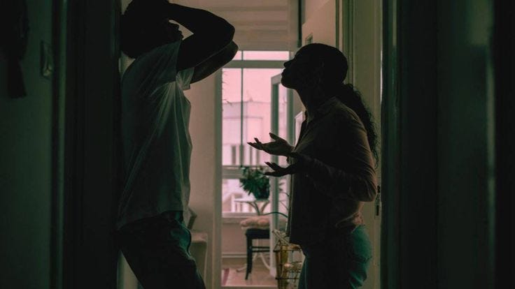 This may contain: a man and woman standing in front of a doorway looking at each other's hands This may contain: a man and woman standing in front of a doorway looking at each other's hands