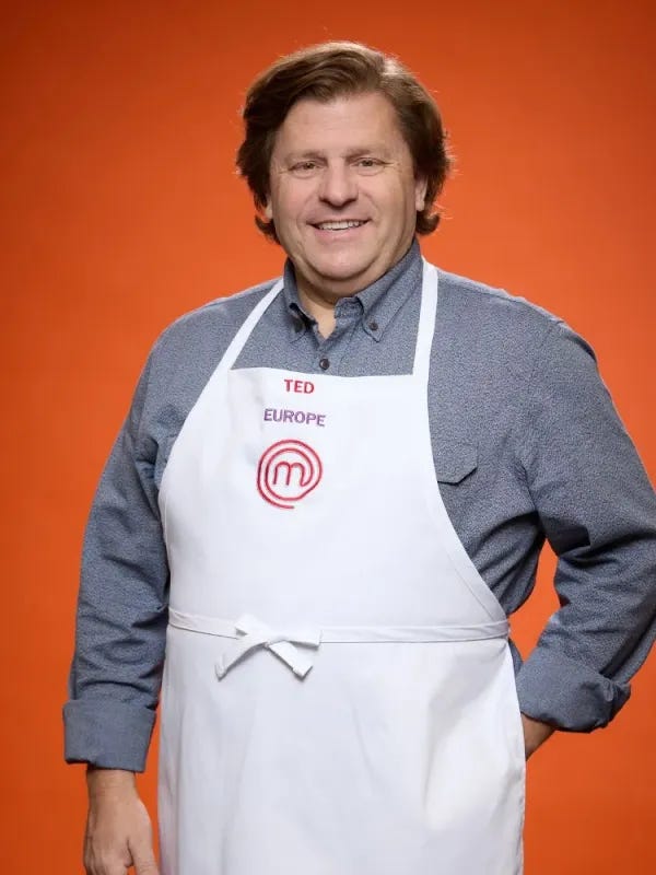 Ted Pappas wear his white chef apron and grey shirt on an orange background Ted Pappas wear his white chef apron and grey shirt on an orange background