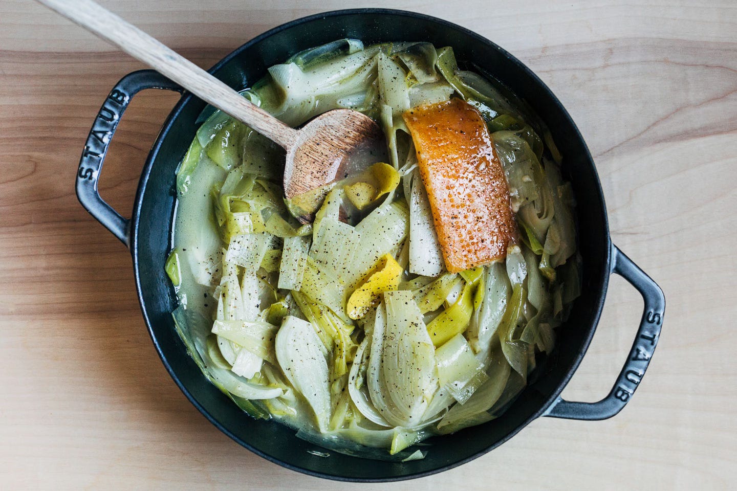A pan with braised vegetables and a Parmesan rind
