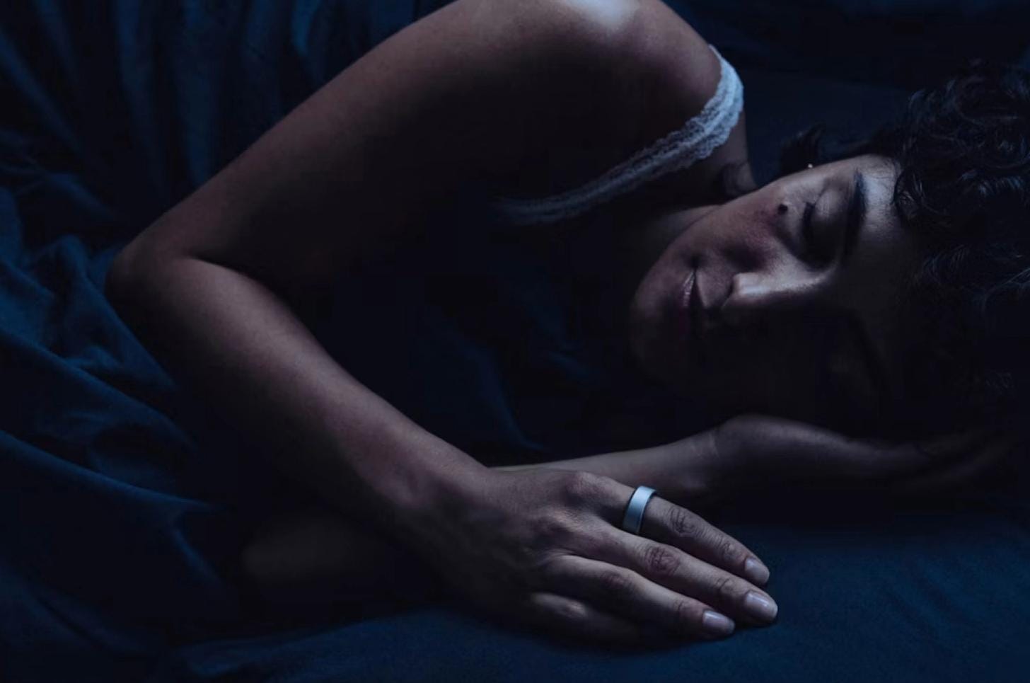 A person sleeping peacefully while wearing an Oura Ring, highlighting the device’s overnight sleep and recovery tracking capabilities. A person sleeping peacefully while wearing an Oura Ring, highlighting the device’s overnight sleep and recovery tracking capabilities.
