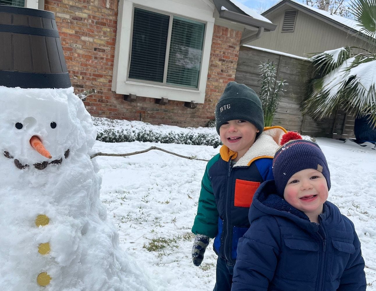 a snowman with two boys standing next to him smiling. a snowman with two boys standing next to him smiling.