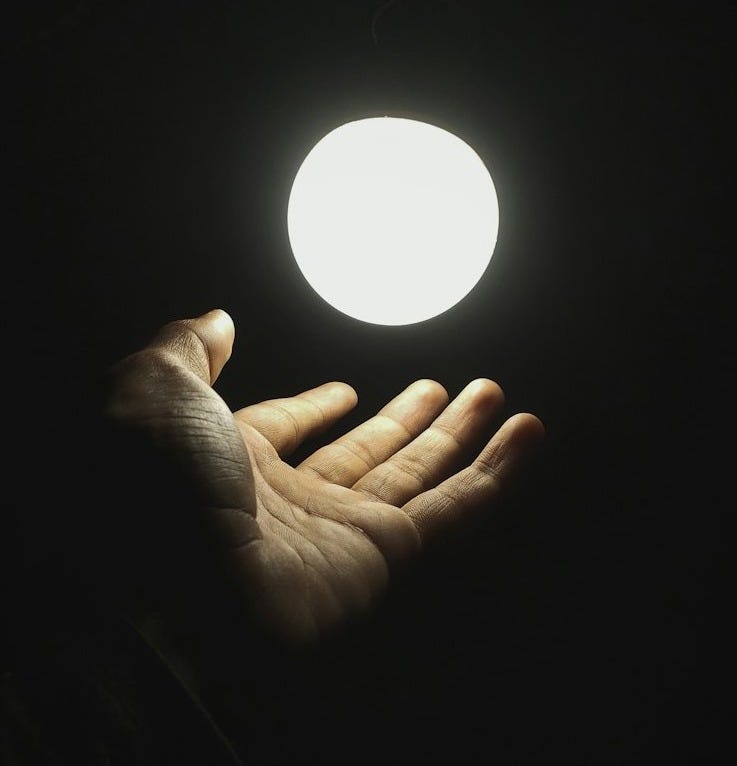 a hand holding a light in the dark a hand holding a light in the dark