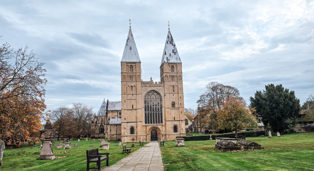 A brown minster with two spires, two lawns either side, and a path in the middle A brown minster with two spires, two lawns either side, and a path in the middle
