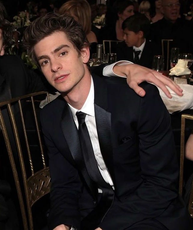 This may contain: two young men sitting next to each other in front of a table full of people