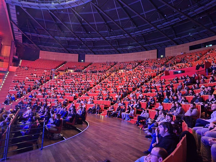 Two pictures from SpeeDons 5 at the Centre de Congrès de Lyon. One shows a view of the crowd in a large amphitheatre-like room, the other one shows the stage with the performers and a large screen behind them.