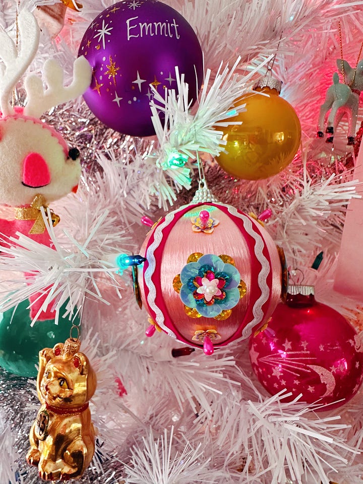 two christmas ornaments. on the left, an ornament made from folded fabric in a quilt pattern. on the right, a pink, satin ornament covered in ribbon and multicolored sequins