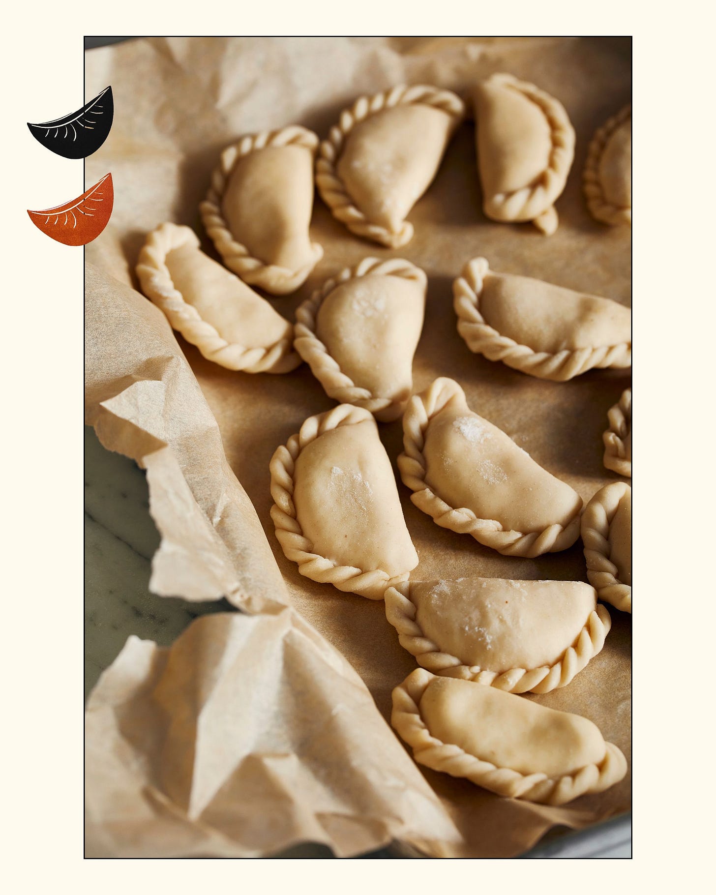 a array of uncooked varenyky sit on parchment on a tray a array of uncooked varenyky sit on parchment on a tray