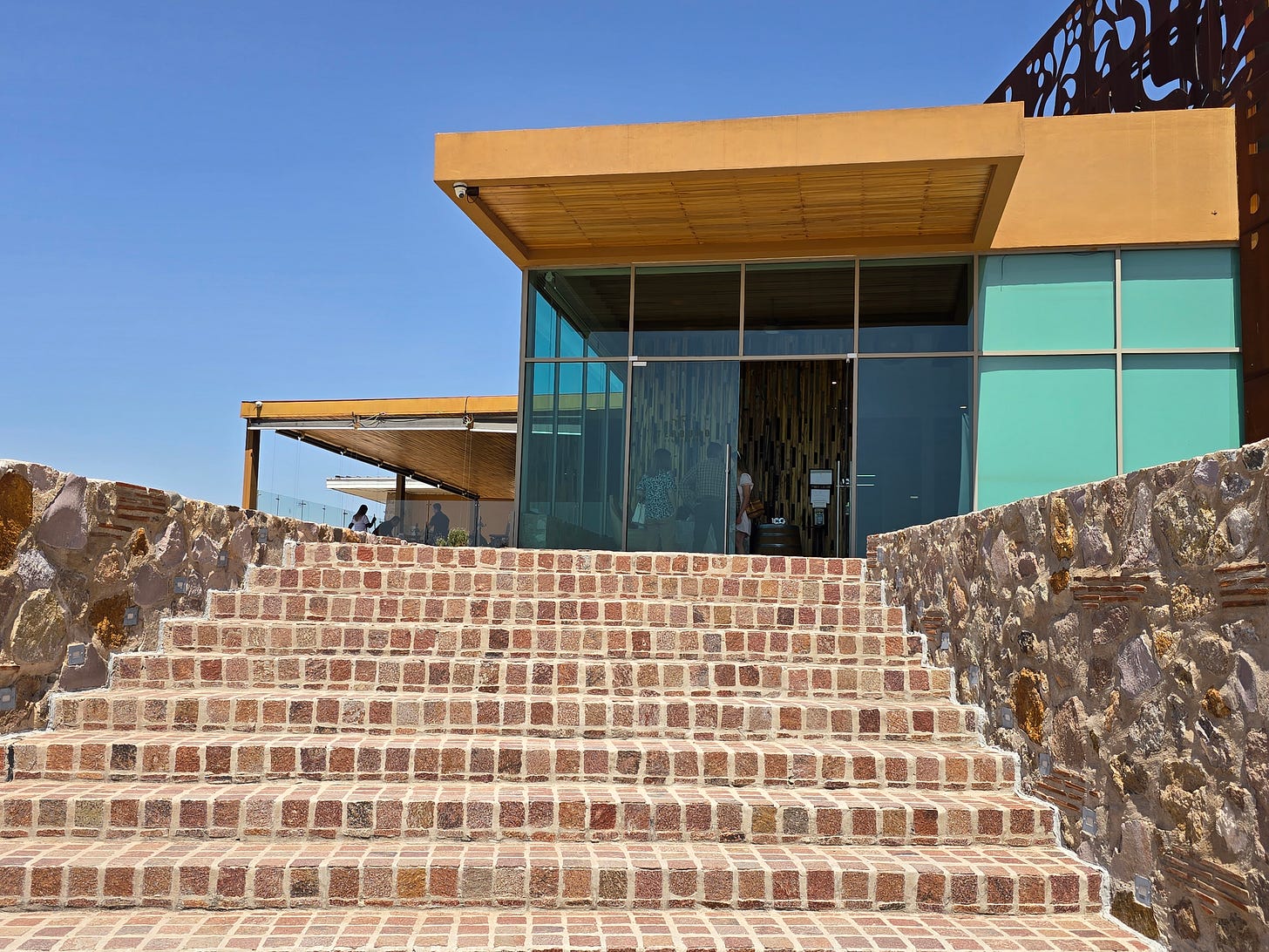 Glass and wood entrance with a brick staircase on a sunny day