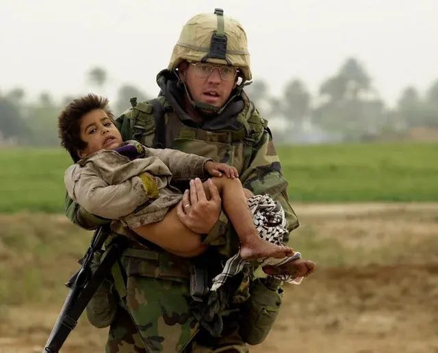 The iconic image of US Iraq War hero Joseph Dwyer carrying an injured Iraqi boy he rescued from crossfire. This moment became a powerful symbol of the human impact of the conflict. The iconic image of US Iraq War hero Joseph Dwyer carrying an injured Iraqi boy he rescued from crossfire. This moment became a powerful symbol of the human impact of the conflict.