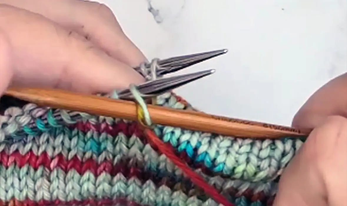 left hand holds two needles and right hand holds one needle