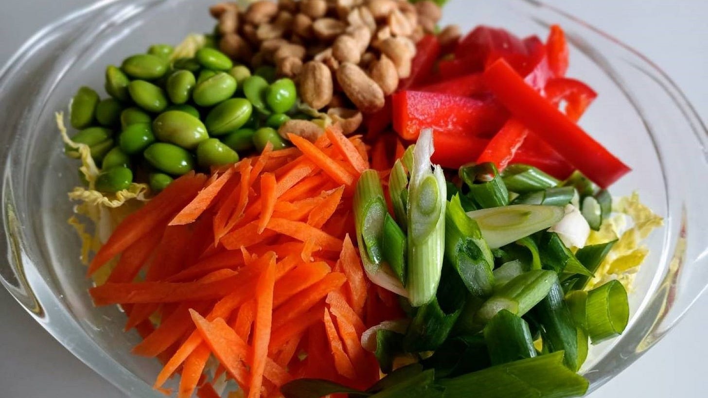 salad with edamame, carrots, peanuts, red peppers, and sliced green onions.