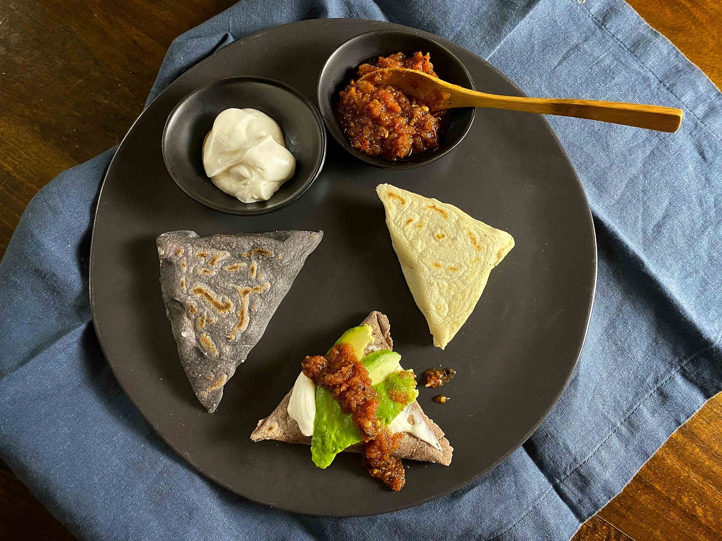 Tetelas filled with mezcal-sautéed mushrooms and quesillo (Oaxaca cheese) and served with crema, salsa roja and sliced avocado