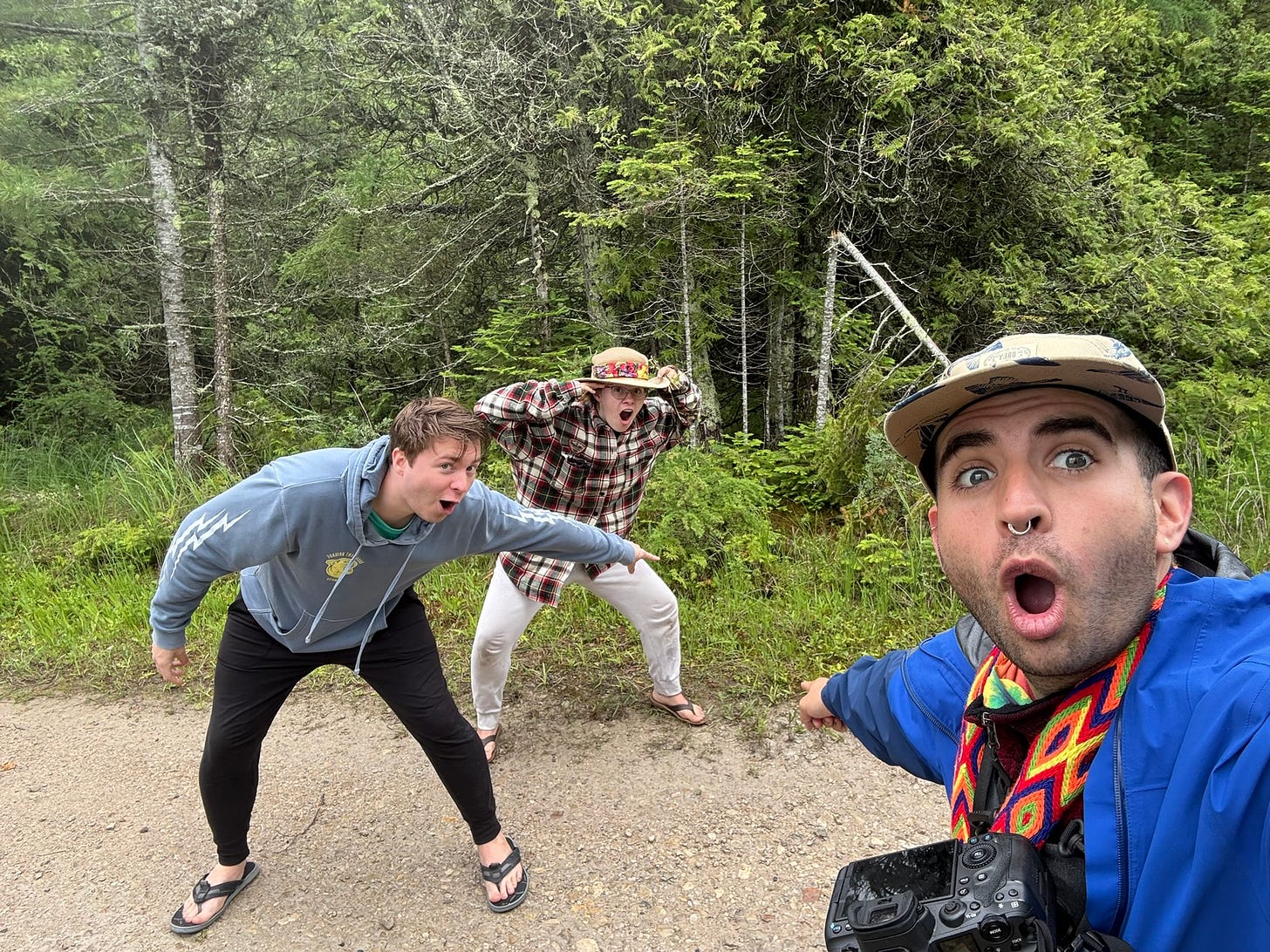 three people standing on a road pointing at the ground behind them with their mouths open, reminiscent of the "soyjak pointing" meme
