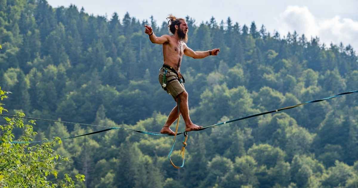 Tightrope walker walking on rope suspended from ground in park