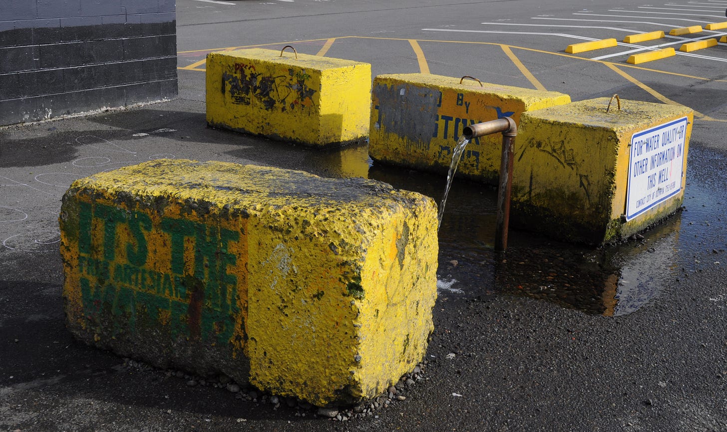 water flowing from a pipe coming out of the ground in a parking lot.