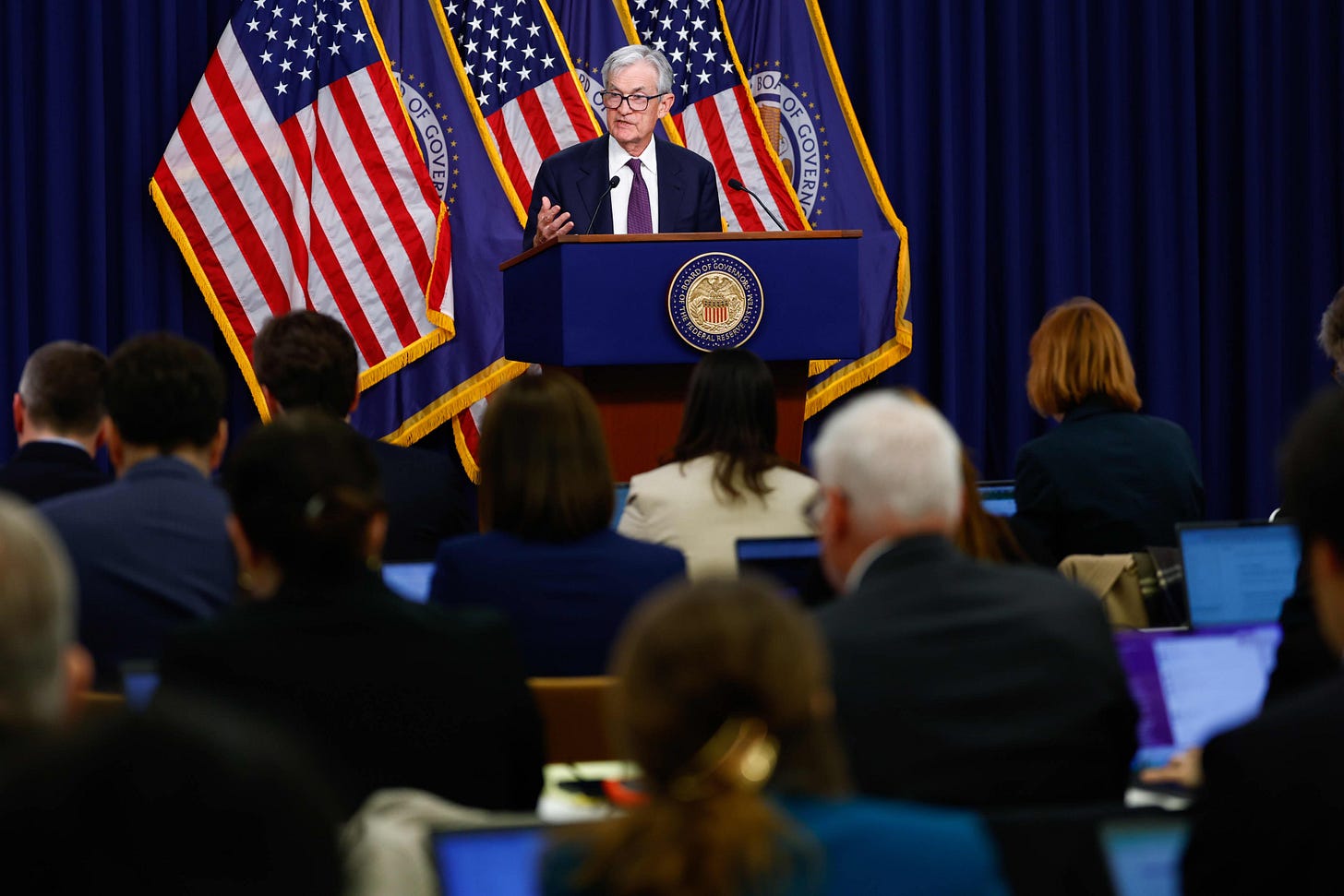 Federal Reserve Chair speaking at an FOMC press conference, explaining the decision to hold interest rates unchanged amid persistent inflation and uncertain market conditions