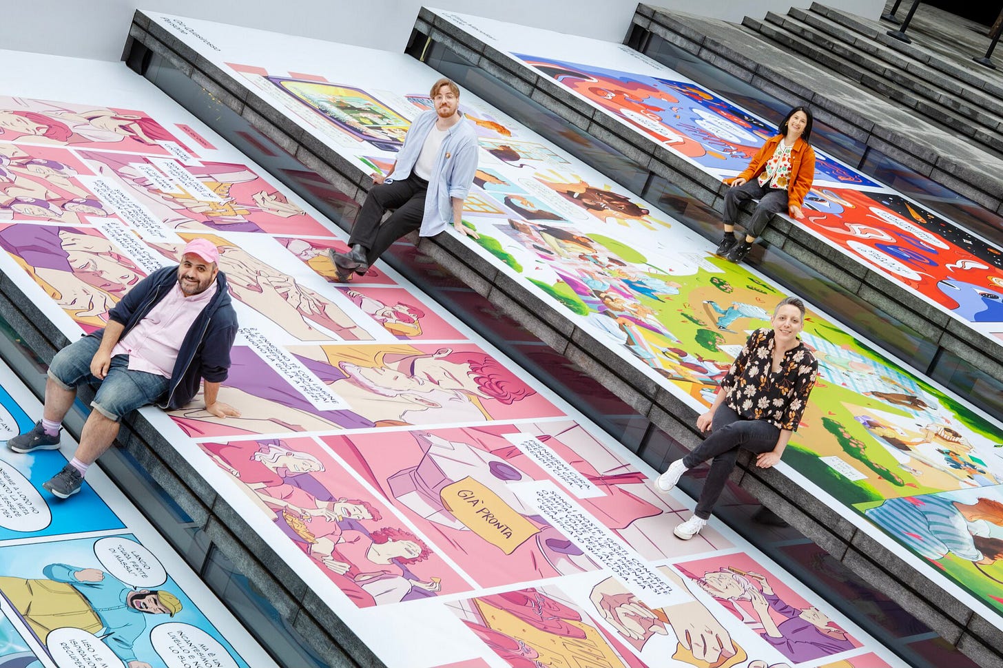 Four artists sit on the steps of Apple Piazza Liberty, which has been decorated in coordination with Illustri Festival for Milan Pride Week.