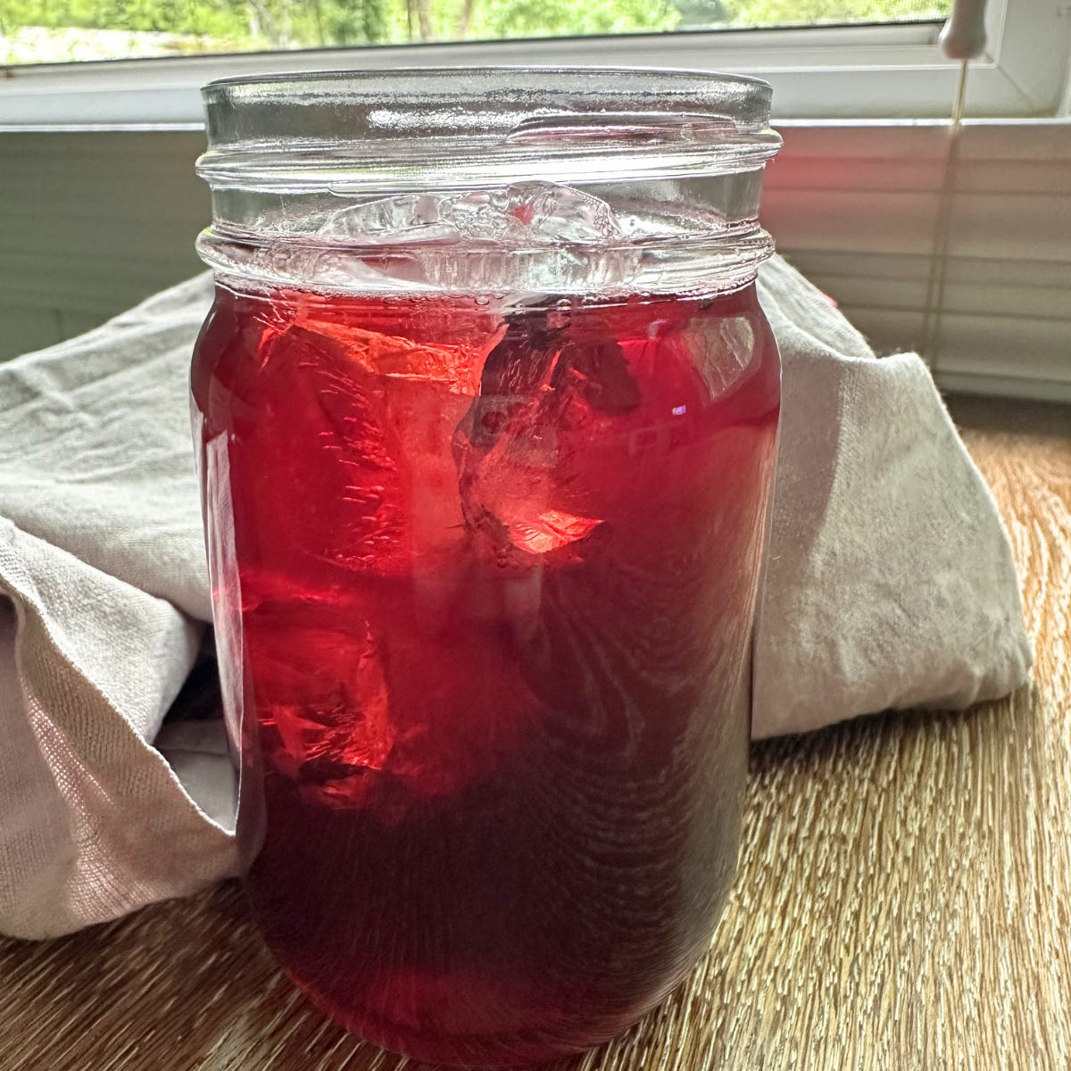 Hibiscus cinnamon tea in a glass mason jar on wood table