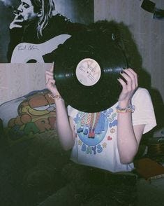 This may contain: a woman holding up a record in front of her face