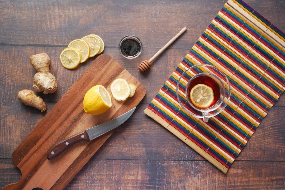 Cutting board, knife, sliced lemons, honey, and ginger root