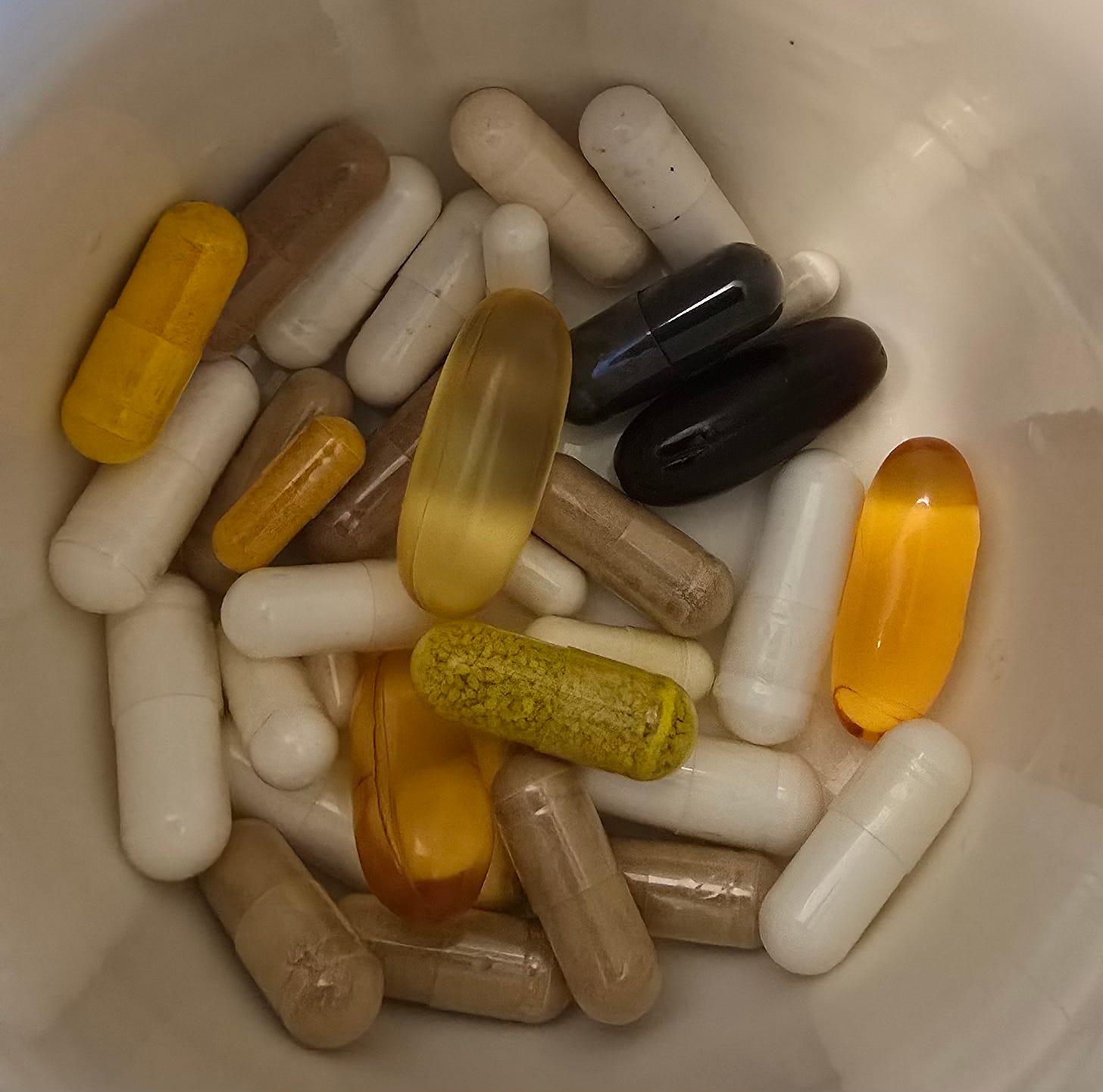 A few dozen supplement pills in a cup.