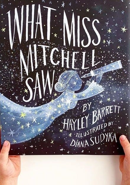 This may contain: a person holding up a book with the title what miss mitchell saw written on it