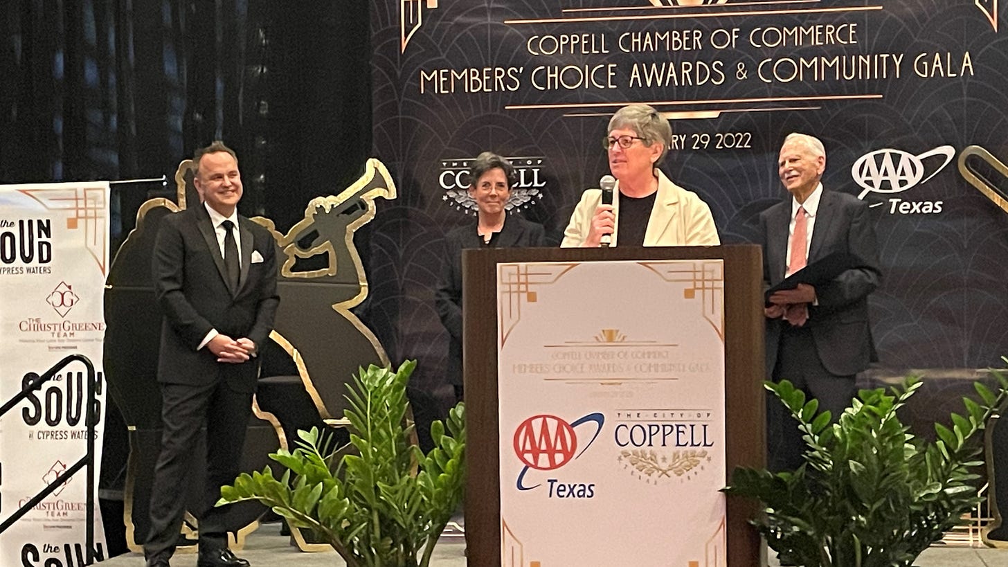Two women and two men on a stage with one of the women speaking