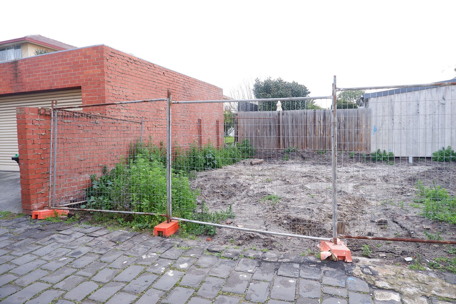 a fenced off block of land. there's a gap in the fence towards the back of the land.