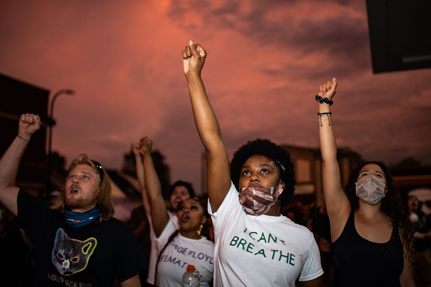 A young black woman wearing an "I can't breathe" t-shirt raises her right fist alongside other protestors A young black woman wearing an "I can't breathe" t-shirt raises her right fist alongside other protestors