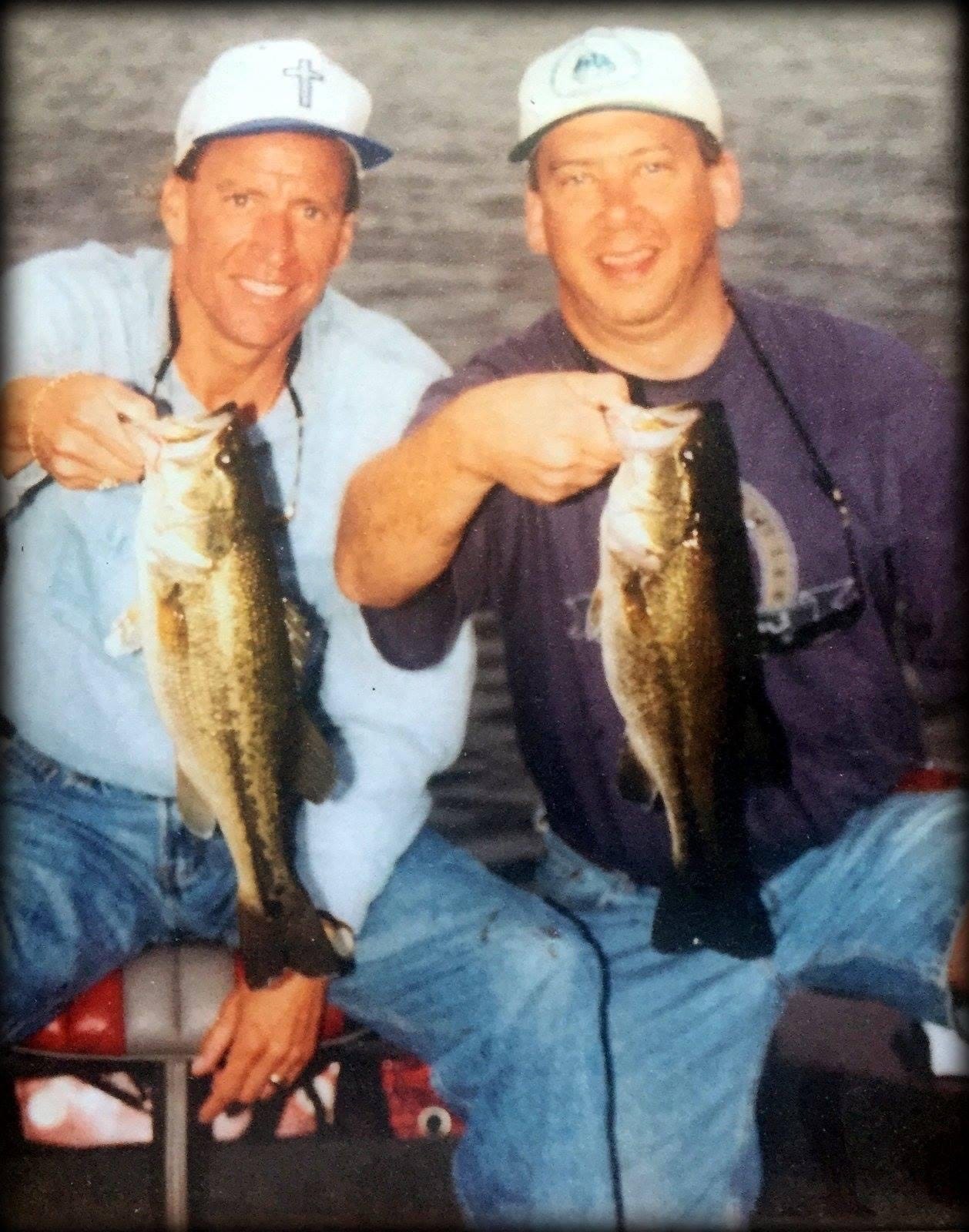 Image of two men holding up largemouth bass in a boat on a lake.
