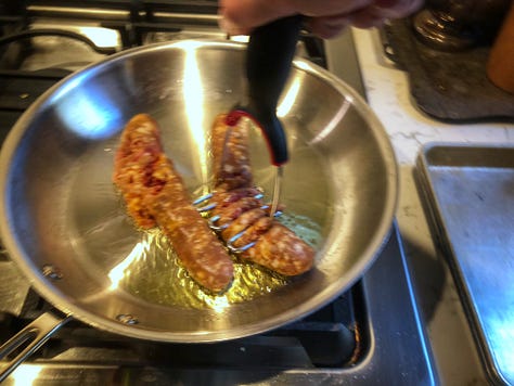 A gallery of five images of the cooking process 1: Oil heating in a pan 2: The sausages being mashed with a potato masher. 3: The cooked sausage on a sheet pan 4: Garlic being added to the pan, which already contains the rapini 5: Three corks jammed under the hande of the pan's lid, creating a handle that's cool to the touch.. 