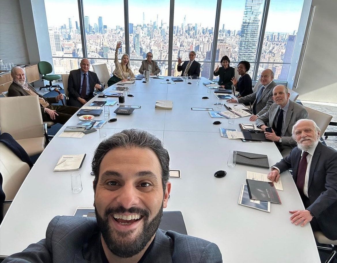 Founder taking a selfie with an engaged board of directors around a conference table overlooking a city skyline.