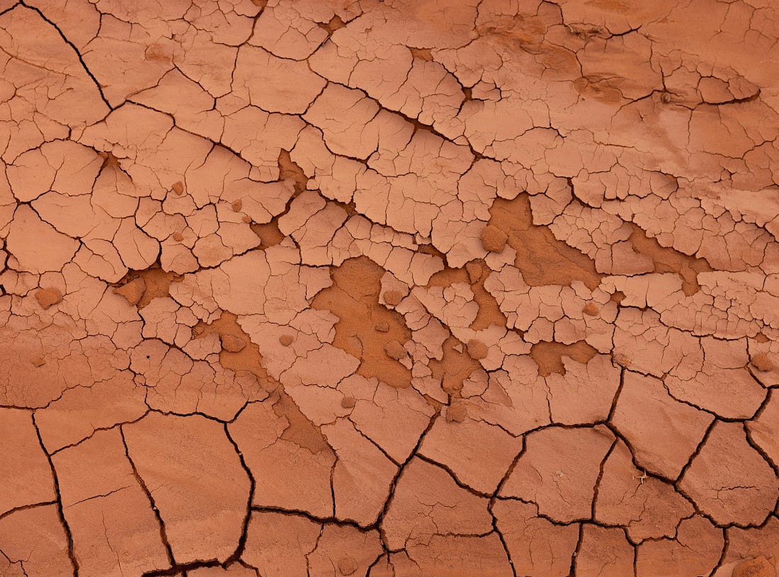 Cracked red clay near Sand Springs in Monument Valley, the surface broken into dry, jagged patterns that hint at drought conditions.