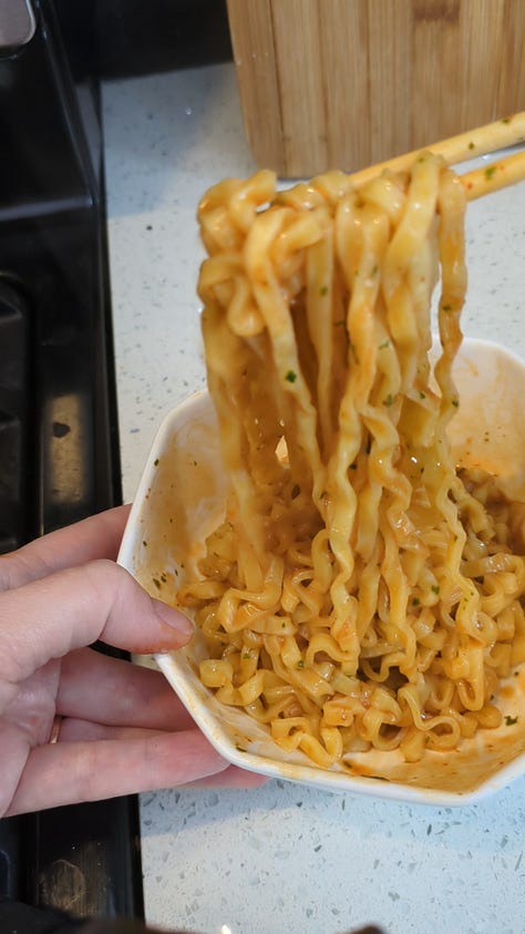 Buldak carbonara packet being opened, cooked, sauce packets mixed and finished noodles raised with chopsticks from the bowl.